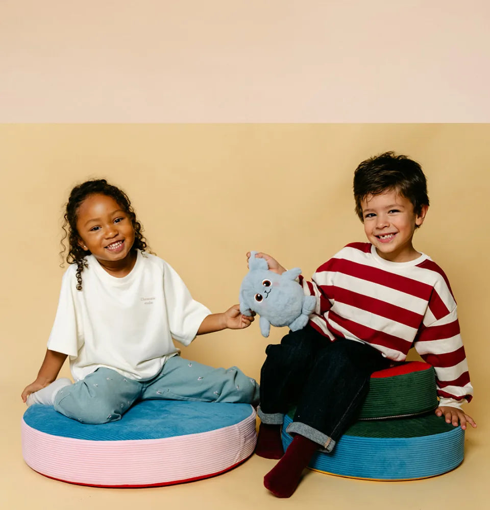 Deux enfants assis sur des poufs avec une peluche Hopi