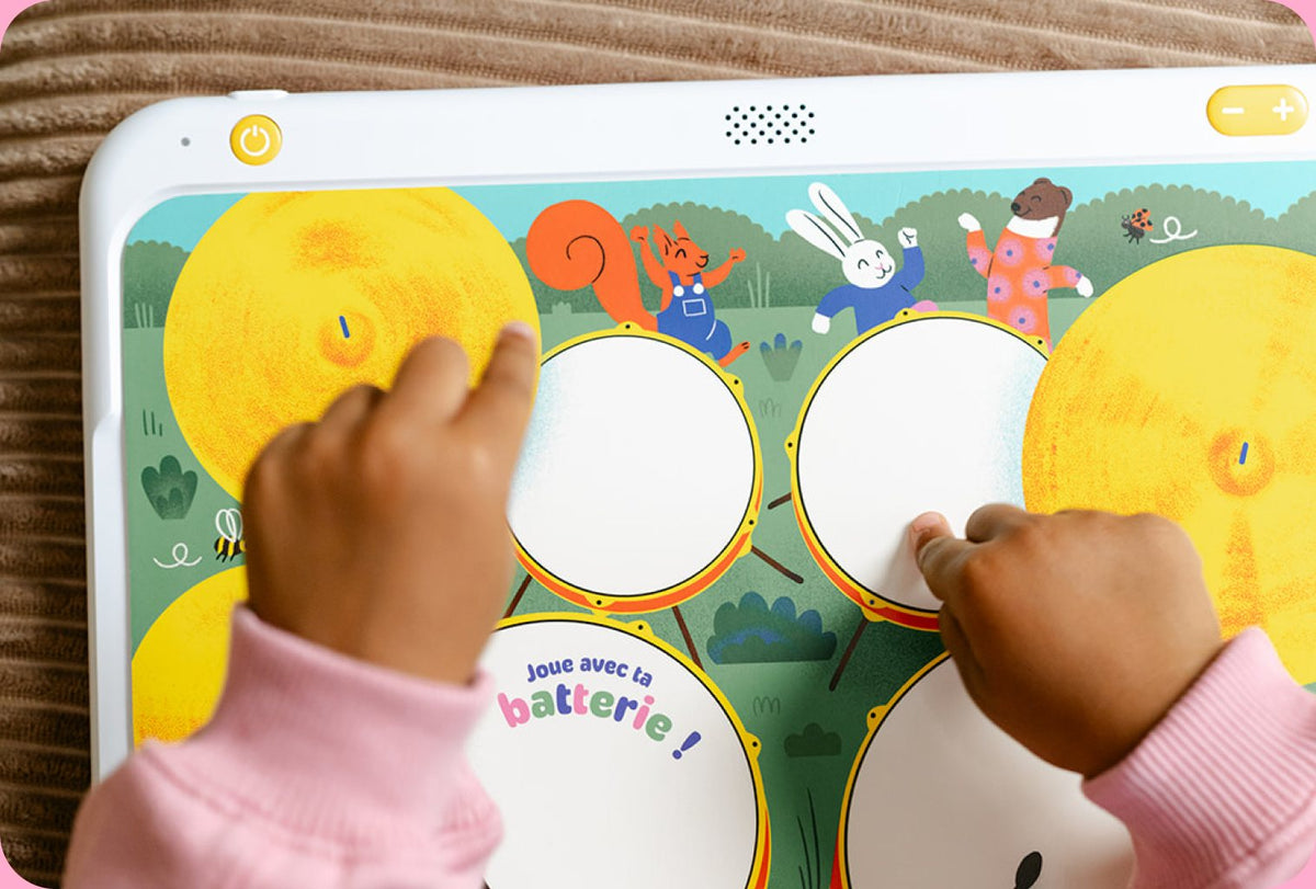 Les mains d'un enfant jouent de la batterie sur un livre HopiPlay