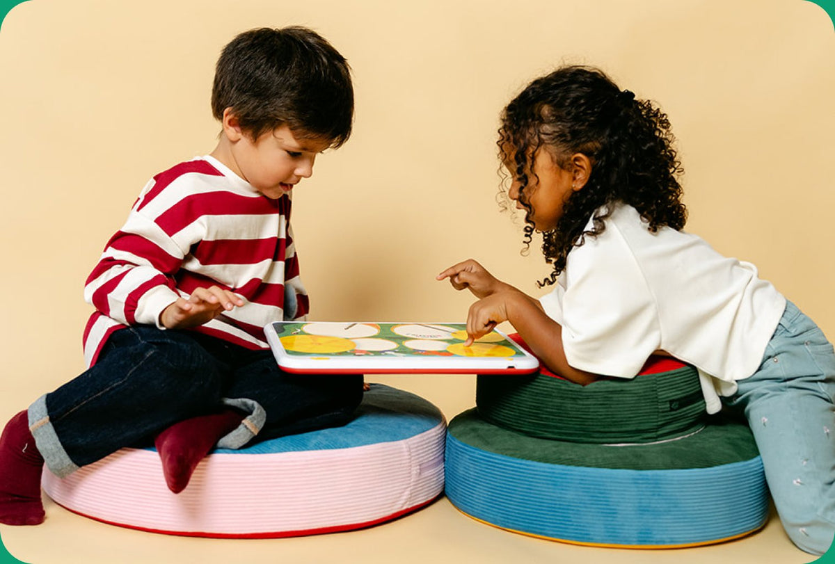Deux enfants assis sur des poufs jouent ensemble avec HopiPlay